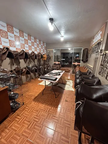 Salão da loja visto de dentro, com selas dos dois lados e a porta de vidro ao fundo