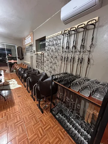 Freios e cabeçadas na parede, selas em cavaletes e uma estante de estribos