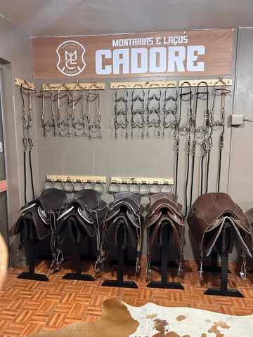 Canto da loja com o letreiro da Cadore, freios pendurados e cinco selas em cavaletes