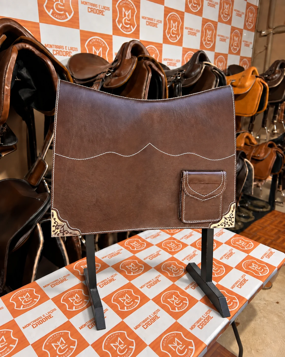 Badana de couro café com costura ondulada, bolso de lapela e cantoneiras de metal trabalhadas