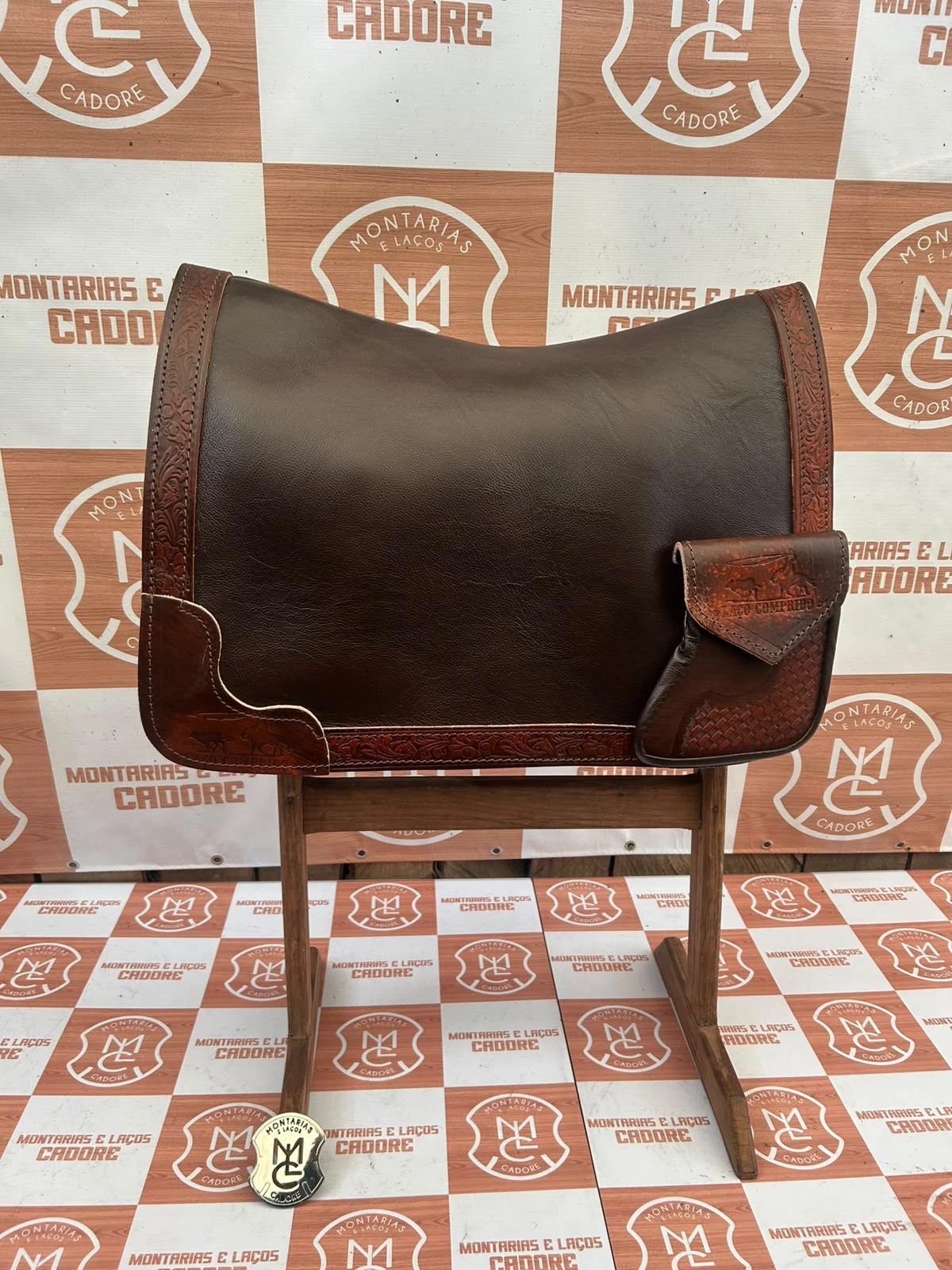 Outra foto da badana de couro cor café com borda trabalhada e bolso personalizado, no cavalete