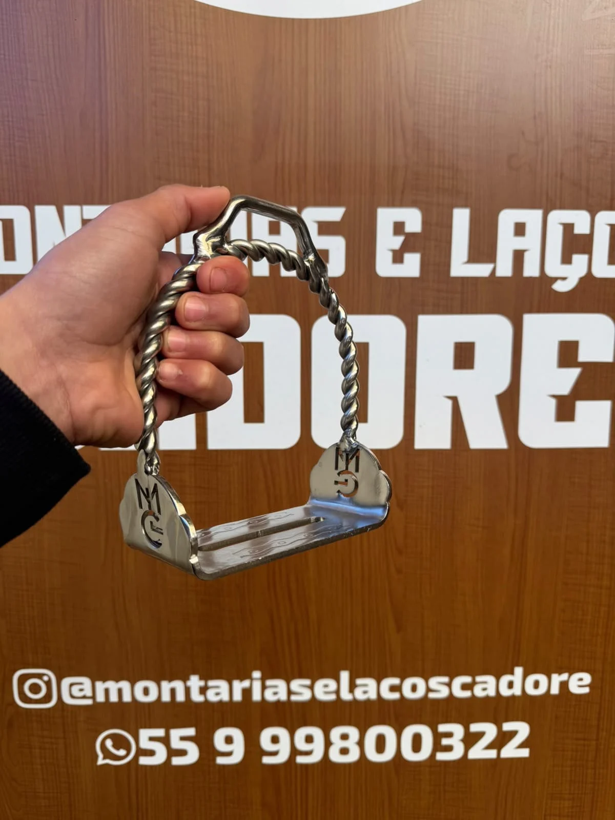 Estribo de inox de base larga, com arco torcido e a logo da loja na lateral
