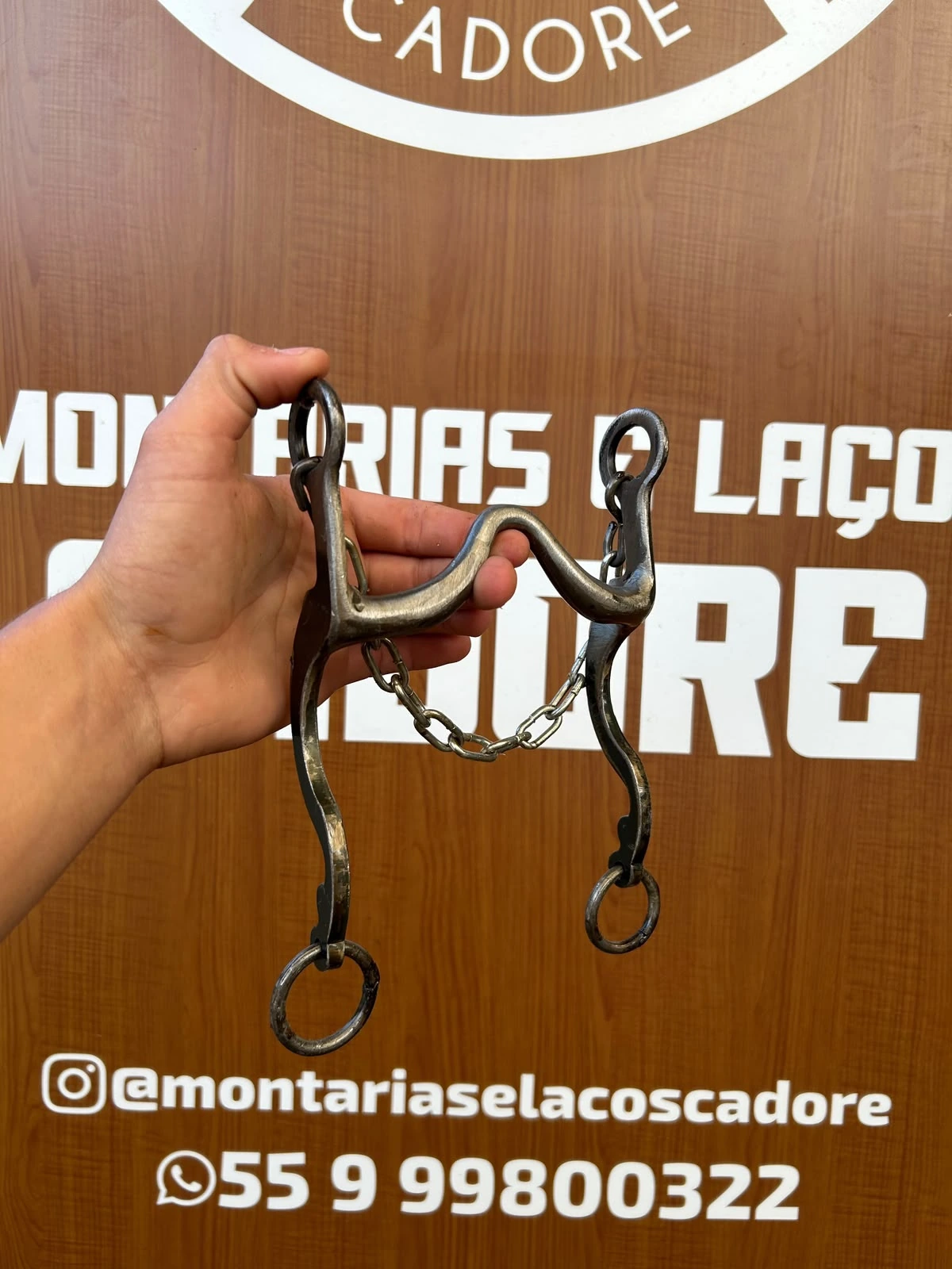 Freio duro de metal com barbela de corrente, seguro na mão em frente ao balcão da loja