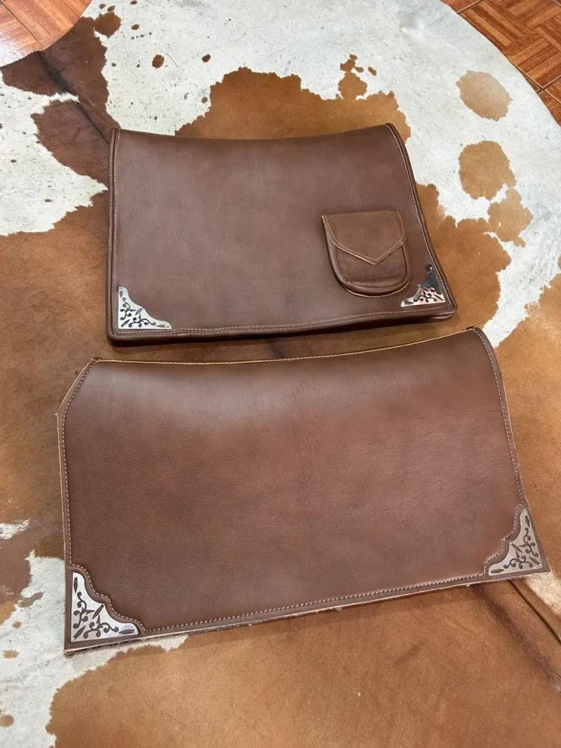 Badana de couro marrom com bolso de lapela e carona de couro, as duas com cantoneiras de metal trabalhadas