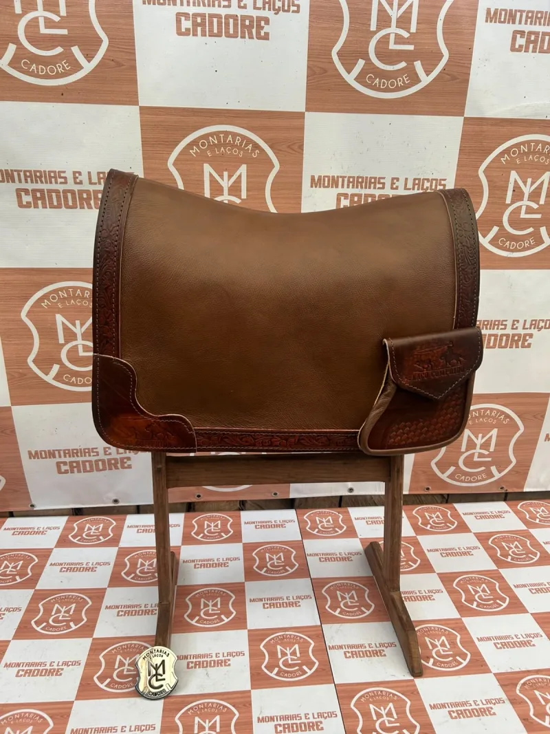 Outra foto da badana de couro marrom com borda trabalhada e bolso personalizado, no cavalete