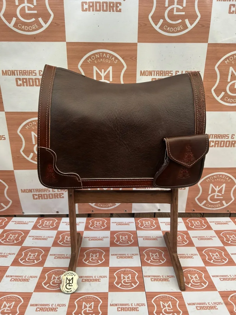 Badana de couro cor café com borda trabalhada e bolso personalizado, sobre cavalete na loja