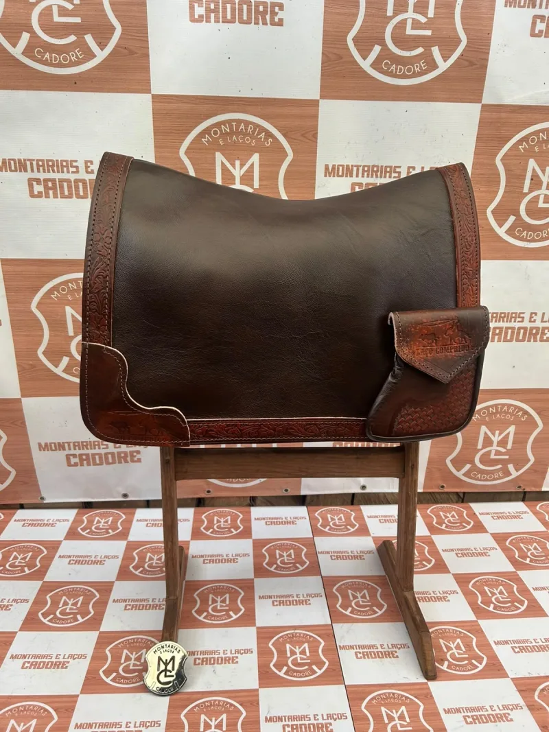 Outra foto da badana de couro cor café com borda trabalhada e bolso personalizado, no cavalete