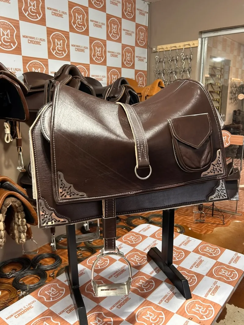 Badana de couro café com bolso de lapela e argola, cobrindo a sela, com cantoneiras de metal trabalhadas