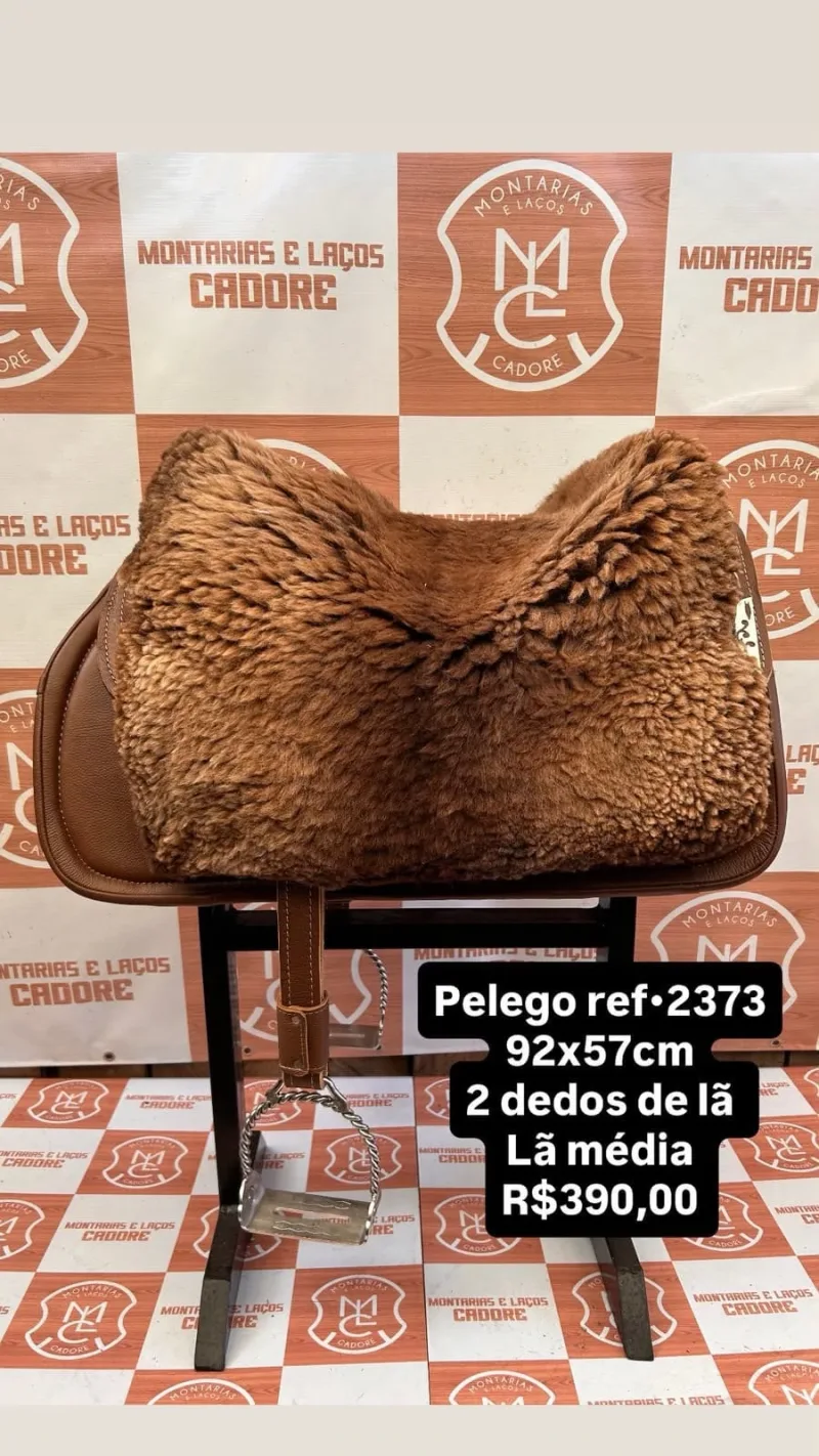 Pelego de lã marrom claro sobre uma sela no cavalete, com a referência 2373, a medida e o preço escritos na foto